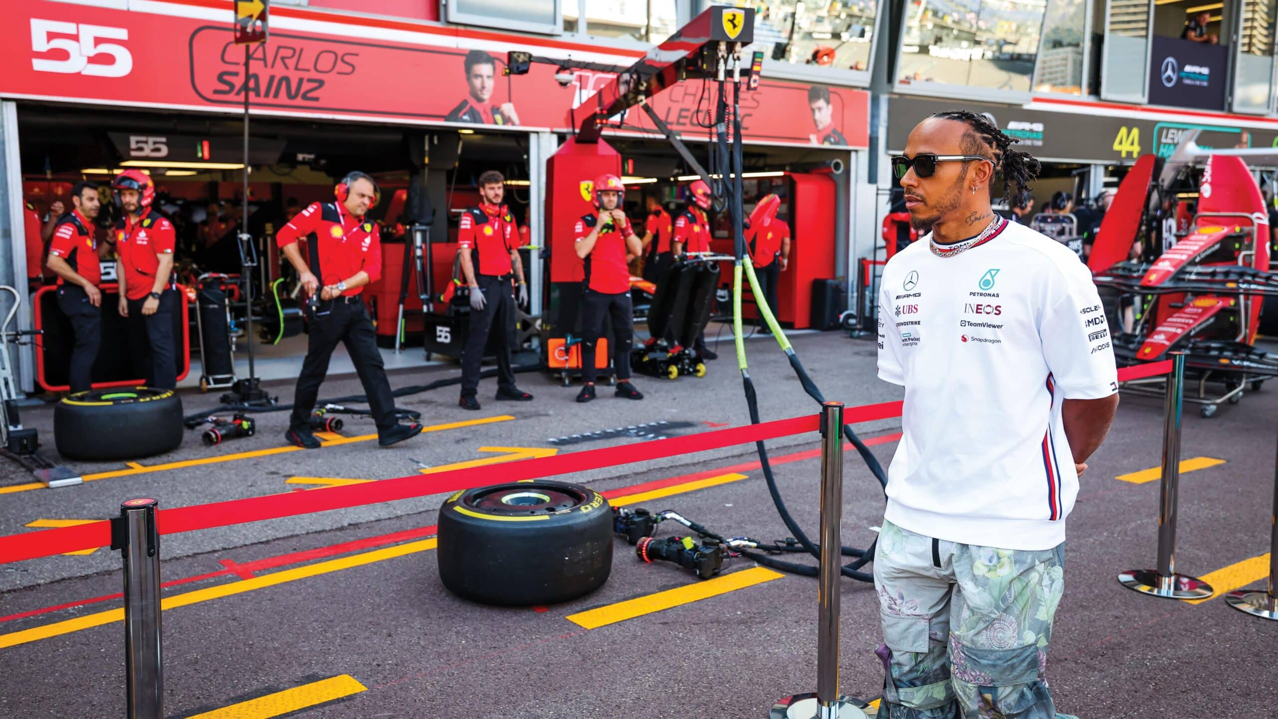 Lewis Hamilton stands infront of Ferrari Pit Team