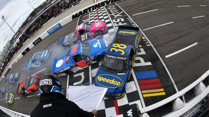 NASCAR trucks spin as white flag is waved