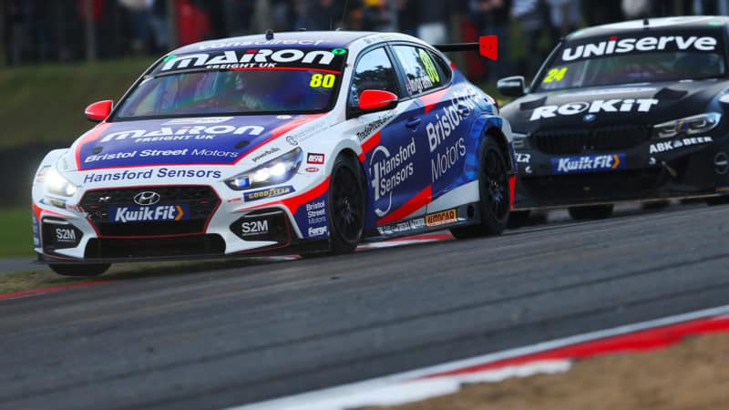 Tom Ingram holds the BTCC championship trophy in the air after winning the 2022 title